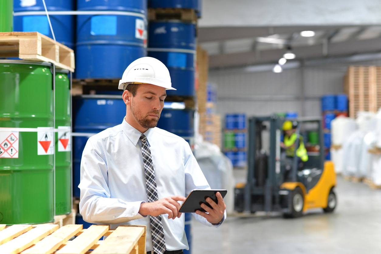manager in a logistic company work in a warehouse with chemicals – checking goods with tablet