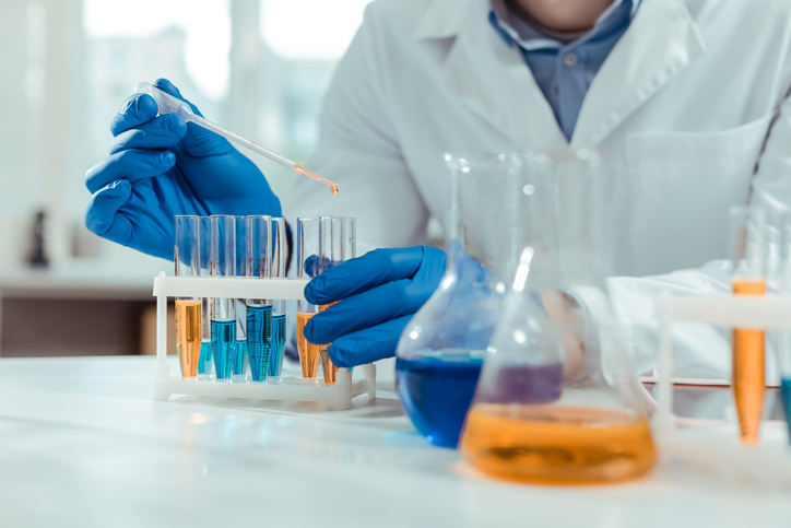 Close up of lab worker using test tubes during chemical formulation