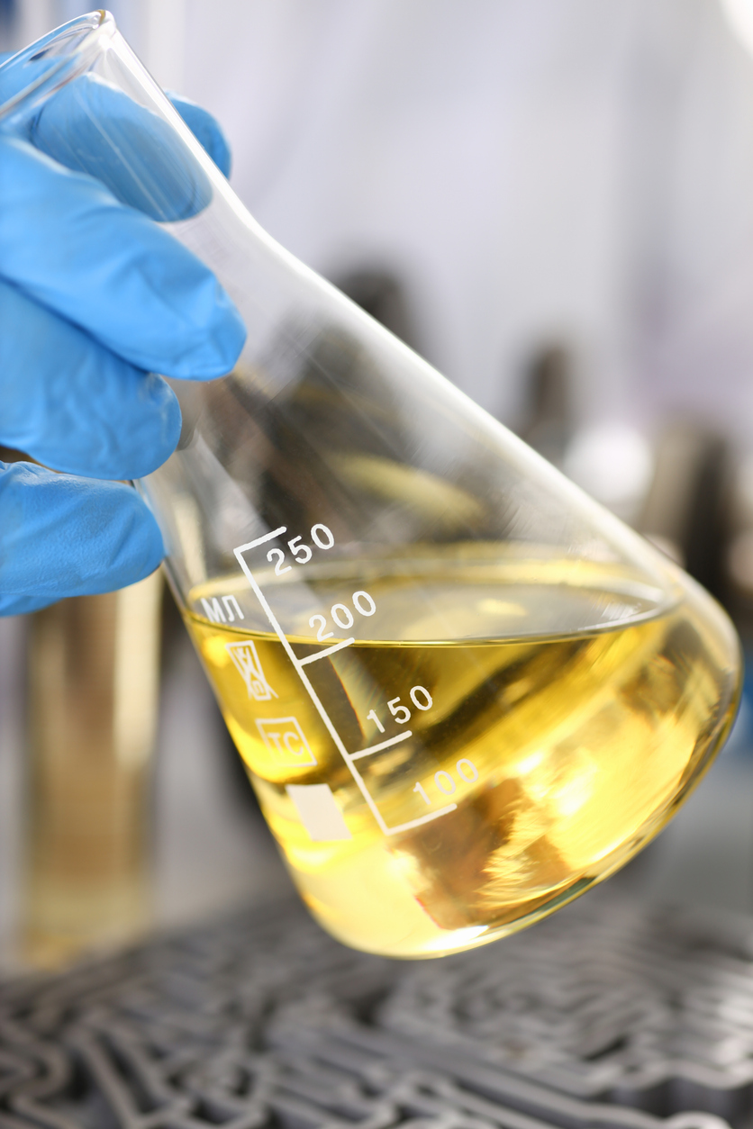 Male hands in protective gloves hold test tube Gloved hands holding a beaker during chemical manufacturing NZ service